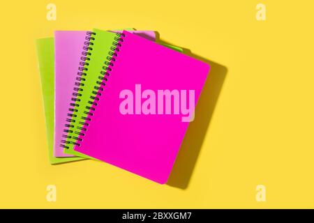 Helle Schulbedarf, Notizbücher auf gelbem Hintergrund. Draufsicht, flaches Lay. Kopierbereich. Stockfoto