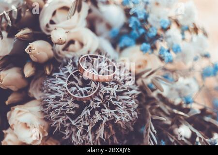 Nahaufnahme der Hochzeitsringe auf rustikalem Blumenstrauß Stockfoto
