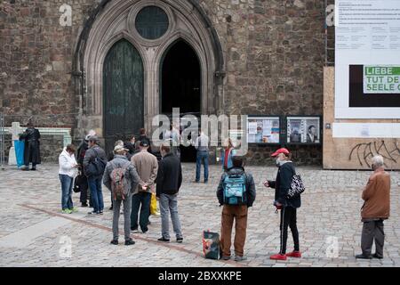 Eine Gruppe von Menschen, die in einer Schlange vor einer Kirche in Berlin auf kostenloses Essen warten. Marienkirche Stockfoto