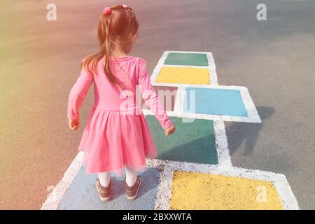 Kleines Mädchen in einem rosa Kleid spielen hopscotch auf Spielplatz im Freien, Kinder Aktivitäten im Freien Stockfoto