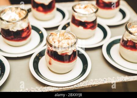 Glassreihen mit weiß-rotem Süßdessert, darüber mit Cashewnüssen verziert. Selbstbedienungsbuffet. Feier, Party, Geburtstag oder Hochzeit Stockfoto