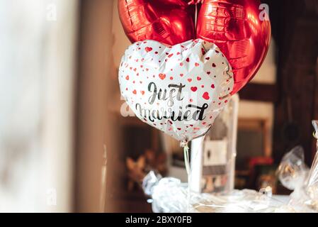 Romantische Gruppe von aufgeblasenen Kunststoff-Ballon in Herzform. Ein weißes Stück mit roten Herzen und Schriftzug 'Just Married' und zwei roten Farben. Stockfoto