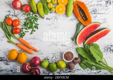 Verschiedene Früchte und Gemüse (Mango, Apfel, Orange, Mandarine, Tomaten, Karotten, Melone, Spinat, Granatapfel, Papaya, Weizengras) auf weißem Rücken Stockfoto