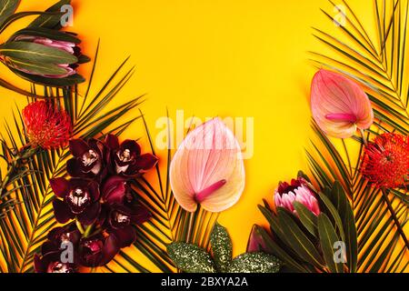 Orchidee, Anthurium, protea und Palmenblätter auf gelbem Hintergrund. Tropische Blumen flach legen Muster mit Platz für Text. Stockfoto