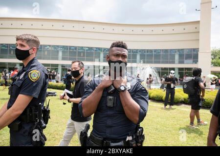 Polizeibeamte in Gesichtsmasken überwachen die große Menge, die in der Linie wartet, um durch das Heiligtum an der Fountain of Praise Kirche im Südwesten von Houston während eines sechs-stündigen öffentlichen Besuchses für GEORGE FLOYD, einen schwarzen Mann, der vor zwei Wochen von einem weißen Polizeibeamten in Minneapolis getötet wurde, zu Datei. Floyds Tod löste weltweite Proteste gegen Rassismus und Polizeibrutalität aus. Stockfoto