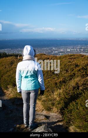 Tourist, der sich nach einer Wanderung ausruhen und die wunderschöne Aussicht auf Dublin, grüne, hügelige irische Hügel und Berggipfel genießen kann. Blick von 3 Rock, Wicklow Mountai Stockfoto