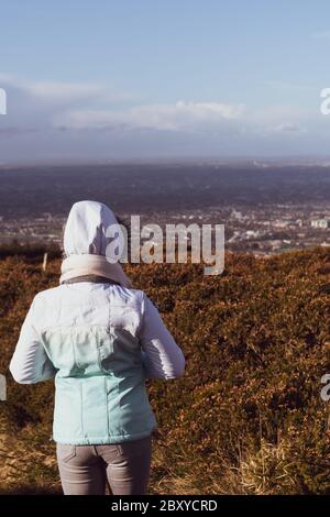 Tourist, der sich nach einer Wanderung ausruhen und die wunderschöne Aussicht auf Dublin, grüne, hügelige irische Hügel und Berggipfel genießen kann. Blick von 3 Rock, Wicklow Mountai Stockfoto