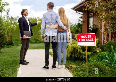 Immobilien-Broker zeigt Haus zum Verkauf an junge Paar, außerhalb Stockfoto