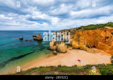 Blick auf einem tollen Strand mit goldener Farbe Felsen in Alvor, Algarve, Portugal. Anzeigen von Cliff Felsen am Strand von Alvor, Algarve, Portugal. Stockfoto