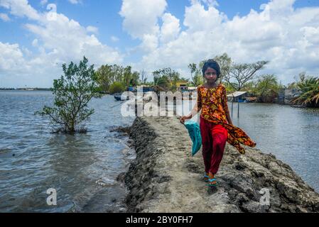 Satkhira, Bangladesch. Juni 2020. Ein Mädchen geht nach dem Landfall des Zyklons Amphan durch einen schlammigen Weg an der Küste.Tausende von Garnelengehegen wurden weggespült, während zahlreiche Strohhäuser, Bäume, Strom- und Telefonmasten, Deiche und Groplande wurden beschädigt und viele Dörfer wurden von der Flutwelle des Amphan im Satkhira Distrikt versenkt. Kredit: Piyas Biswas/SOPA Images/ZUMA Wire/Alamy Live News Stockfoto