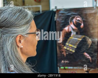 Eine Touristen-Dame mittleren Alters, die sich Kunstwerke anschaut, die einen Tango-Spieler auf dem Kunsthandwerksmarkt San Telmo in Buenos Aires zeigen Stockfoto