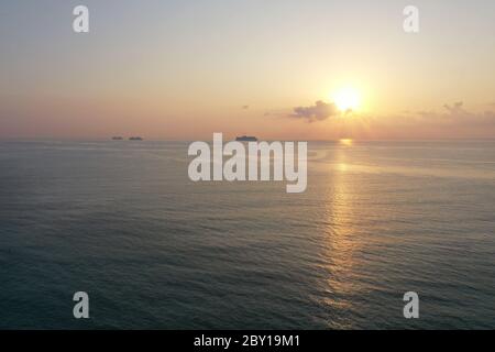 Luftaufnahme des Sonnenaufgangs über dem Ozean von Miami Beach, Florida mit Kreuzfahrtschiffen vor Anker am Horizont. Stockfoto