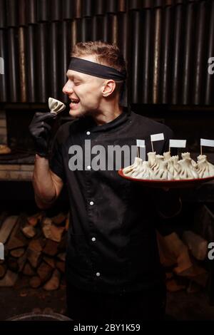 Fröhlicher Koch posiert mit einer Portion Krinkali. Georgische nationale traditionelle Küche. Garvorgang. Küche. Food Konzept Stockfoto