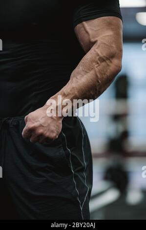 Testosteron Konzept des Körpers Körperbau Teil der starken männlichen in schwarzen Sportbekleidung zeigt starke Arme mit großen Vene während des Fitness-Studio-Training Stockfoto