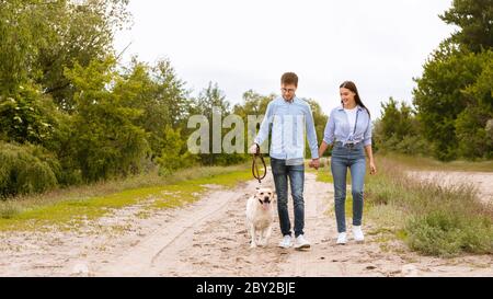 Aufgeregt paar und golden Retriever Wandern in der Landschaft Stockfoto