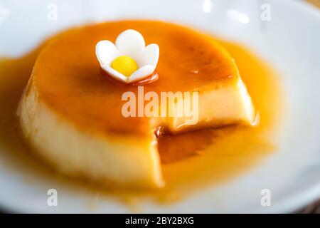 Nahaufnahme von hausgemachtem Karamell-Pudding auf weißem Teller mit selektivem Fokus Stockfoto