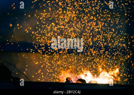 Flamme und Feuerfunke mit Bokeh aus brennender Kohle auf dunklem abstraktem Hintergrund Stockfoto