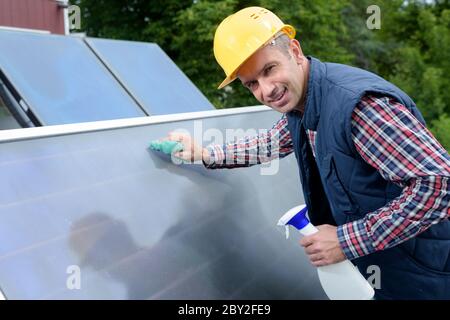 Ein Mann, der Sonnenkollektoren reinigt Stockfoto