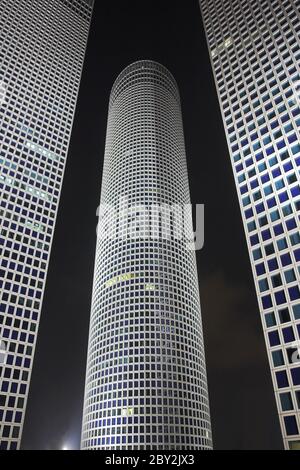 Runde, quadratische und dreieckige Wolkenkratzer bei Nacht Stockfoto