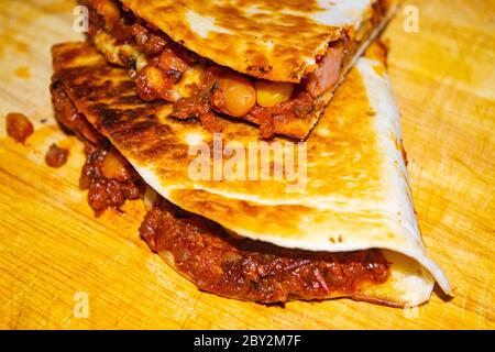 Quesadilla mit Hackfleisch, Wurst, roten Bohnen, Mais, Zwiebeln und Tomatensauce. Ein traditionelles mexikanisches Essen. Nahaufnahme Stockfoto