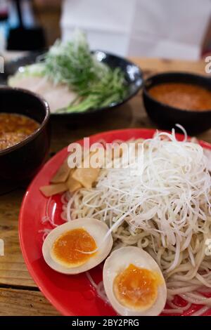 Japanische Hiroshima traditionelle Brühe Ramen Nudeln mit weich gekochten Eiern auf dem Holztisch serviert Stockfoto