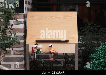 Holztafel mit Puppendekorationen vor dem Restaurant. Stockfoto