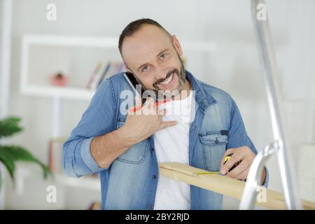 Mann, der am Telefon telefonieren und mit Holz arbeiten Stockfoto