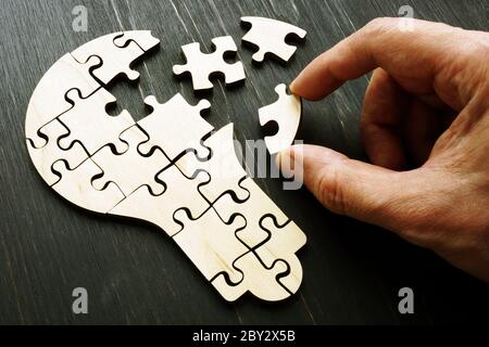 Eine Hand sammelt ein Puzzle in Form einer Glühbirne als Symbol für eine neue Idee, Kreativität und Startup. Stockfoto