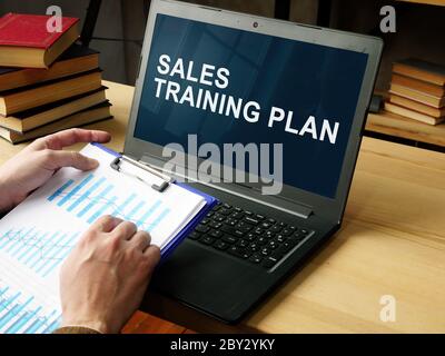 Manager liest den Sales Training Plan auf dem Laptop. Stockfoto