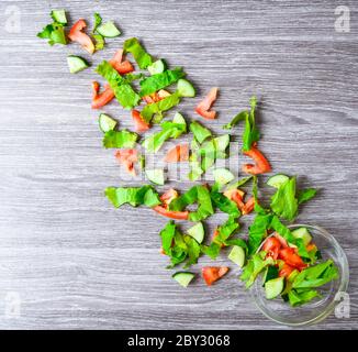 Fliegender Salat auf Holz in Schüssel, in Scheiben geschnittene Gurken-Tomatenblätter, grüne Zwiebel, Leinsamen Stockfoto