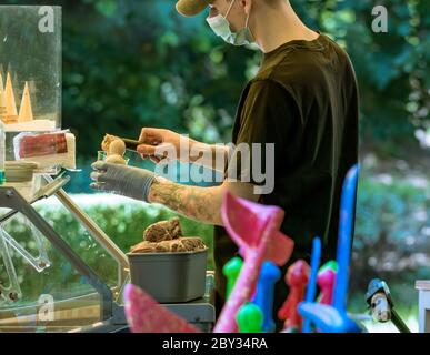 Bukarest/Rumänien - 05.30.2020: Mann, der Eis serviert.Eisverkäufer, der eine Kugel Eis auf einen Kegel legt. Stockfoto