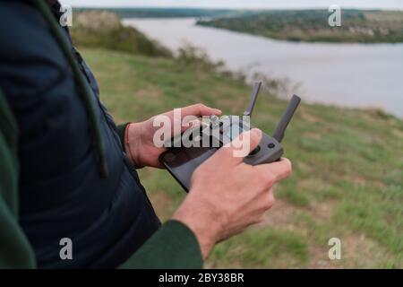 Junger Mann pilotieren Drohne im Freien in der Natur. Guy testen Luft unbemannten Fahrzeug in der Natur. Kulisse für Unterhaltung für Erwachsene Stockfoto