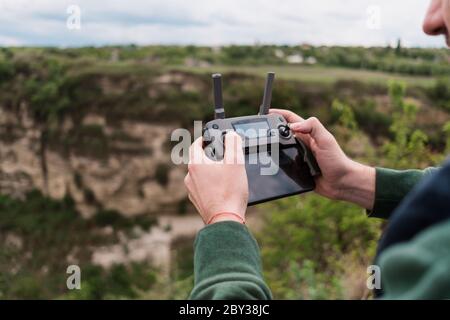 Junger Mann pilotieren Drohne im Freien in der Natur. Guy testen Luft unbemannten Fahrzeug in der Natur. Kulisse für Unterhaltung für Erwachsene Stockfoto