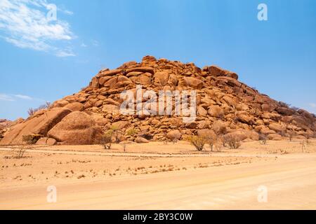 Orange Felsformation in trockener Wüstenlandschaft bei Twyfelfontein in Damaraland, Namibia. Stockfoto