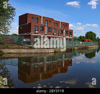 Neue modulare Häuser spiegeln sich im Kanal wider, da sie entlang des Leeds und Liverpool Kanals gegenüber dem Wigan Pier gebaut werden Stockfoto