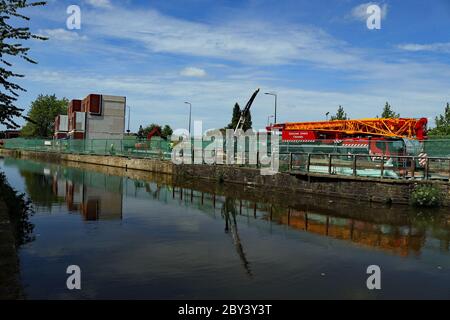 Neue modulare Häuser und ein alter Kran spiegeln sich im Kanal wider, während sie entlang des Leeds und Liverpool Kanals gegenüber dem Wigan Pier gebaut werden Stockfoto