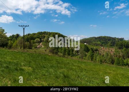 Filipka und Loucka Hügel im Frühling Slezske Beskiden Berge in Tschechien mit Wiese, Wald, Weg, wenige isolierte Häuser und blauen Himmel mit cl Stockfoto