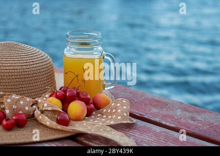 Ein Glas tropischer exotischer Multifruitsaft und Früchte am Pier. Tropisches Picknick am Strand Stockfoto