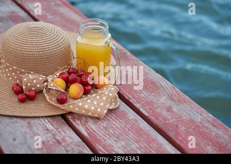 Ein Glas tropischer exotischer Multifruitsaft und Früchte am Pier. Tropisches Picknick am Strand Stockfoto