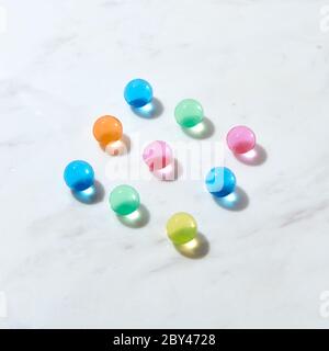 Diagonalmuster aus Hydrogel-Farbkugeln auf einem grauen Marmortisch. Stockfoto