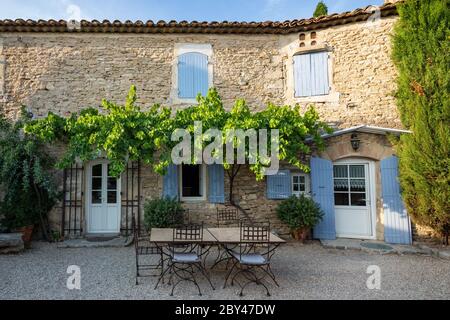 Ein typisches französisches Haus in der Provence, mit blauen Fensterläden und einem Essbereich im Freien Stockfoto