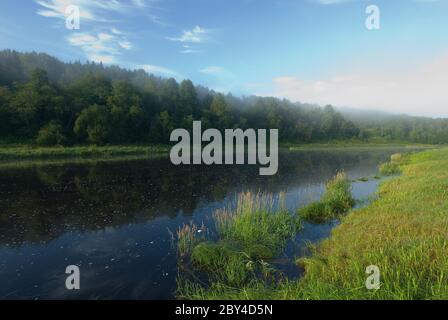 Tiefblaues Wasser des Flusses, grünes Gras und blauer Himmel Stockfoto