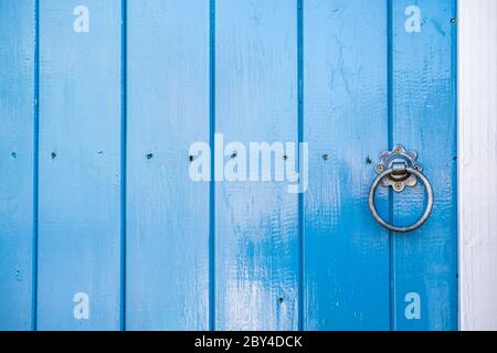 Nahaufnahme einer neu bemalten hölzernen Eingangstür, Teil eines renovierten Häuschens. Zeigt die frische blaue Glanzfarbe und traditionelle Verriegelung. Stockfoto