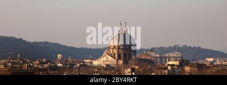 Blick über die Dächer Roms bei Sonnenuntergang im Winter. Die Kuppeln von San Carlo ai Catinari und Sant'Andrea della valle fangen das Abendlicht an. Stockfoto