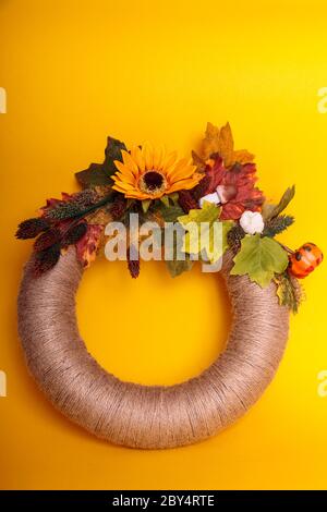 Handgefertigter Kranz aus kleinen Kürbissen und Blumen an einer Vintage-Tür Stockfoto