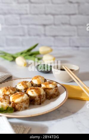 Sushi-Brötchen mit Sauce auf weißem Teller serviert. Hellgrauer Hintergrund. Gemütliches Zuhause Foto Stockfoto