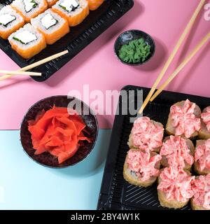 Sushi-Brötchen mit roter Mayonnaise-Sauce und Philadelphia in schwarzer Schachtel. Restaurant-Food-Lieferung in Take Away Boxen Stockfoto