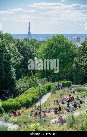 Die Leute im Parc de Belleville genießen den Blick auf den Eiffelturm während des sonnigen Tages nach der Covid-19 Sperre beendet ist Stockfoto