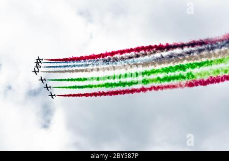 Gruppe von weißen Kampfflugzeugen mit einer Spur von buntem Rauch gegen einen blauen Himmel Stockfoto