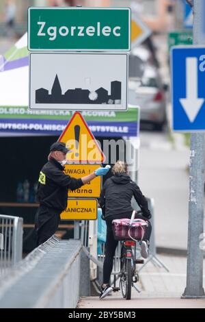 09. Juni 2020, Sachsen, Görlitz: Ein polnischer Grenzpolizist steht auf der Brücke der Freundschaft an der polnischen Grenze vor Zgorzelec und überprüft mit einem Thermometer die Körpertemperatur einer Radfahrerin, die auf die polnische Seite fahren will. Foto: Sebastian Kahnert/dpa-Zentralbild/dpa Stockfoto